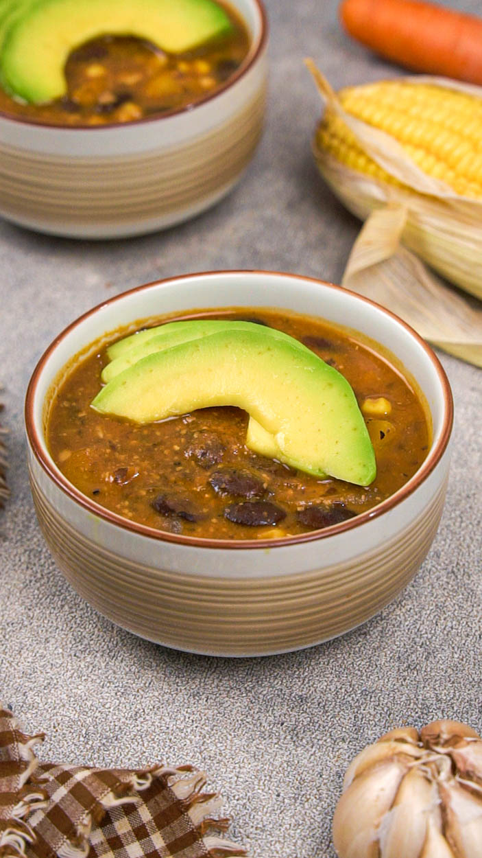 A bowl of black bean and corn soup topped with avocado slices.