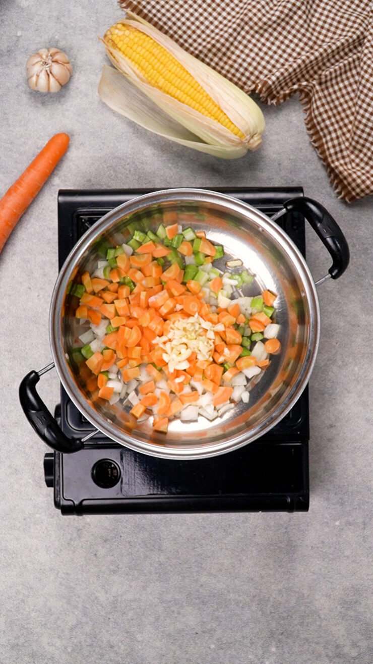 Carrots, garlic and vegetables sizzle in a pan.
