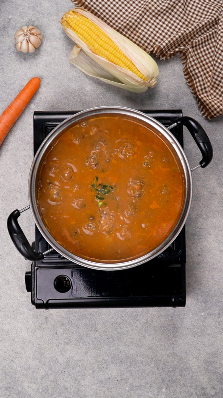 Black bean and corn soup simmers in a pan on the stove.