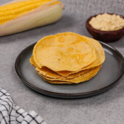 A plate of masa harina tortillas on a countertop surrounded by corn products.