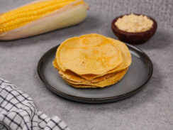 A plate of masa harina tortillas on a countertop surrounded by corn products.