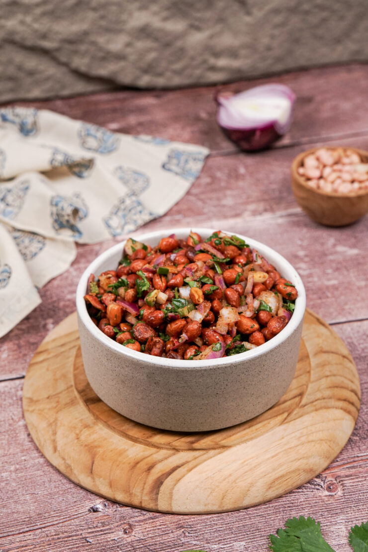 Grayish-white bowl of spicy cocktail peanuts with sauteed red onion, jalapenos, and cilantro.