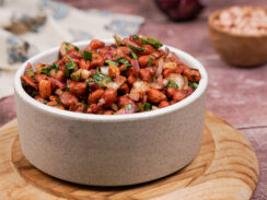 Grayish-white bowl filled with spicy cocktail peanuts with flecks of cilantro, jalapeno, and diced onion through them.