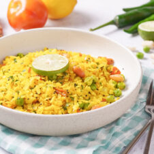 Curried poha rice in a bowl and sitting on a kitchen table. This article is for an easy poha rice recipe.