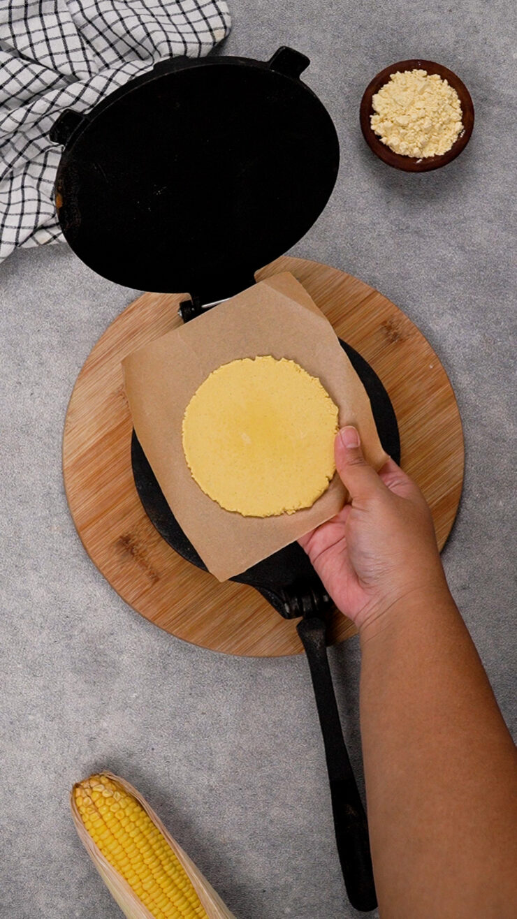 Masa harina tortilla in a grill, with brown baking paper beneath it.