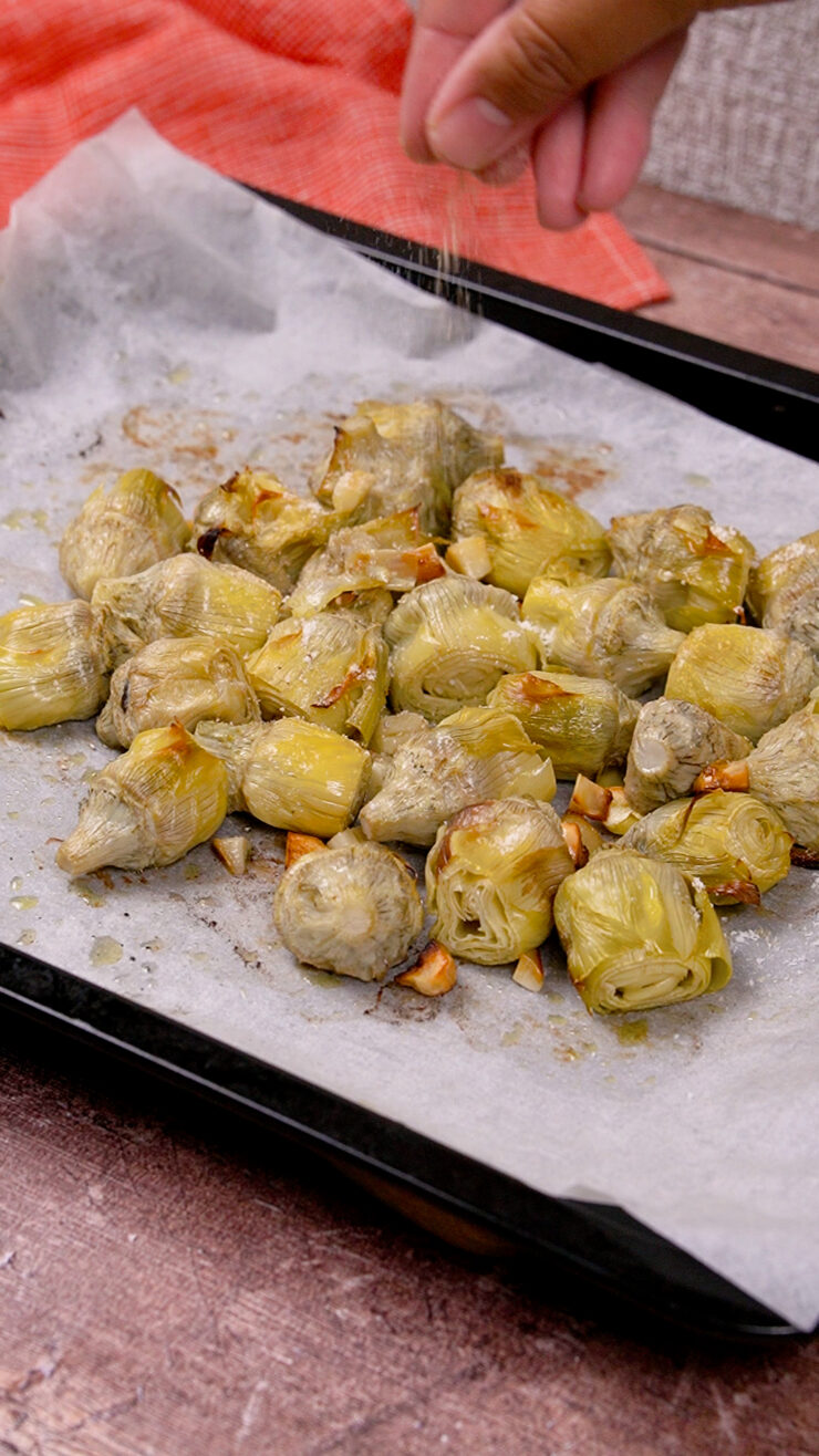Baked artichoke hearts on parchment paper, drizzled in garlic and olive oil.