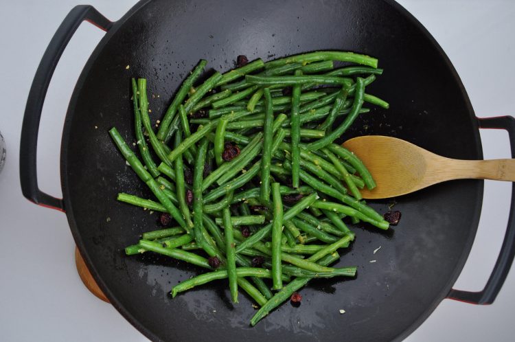 Green beans in a wok seasons with salt and sugar