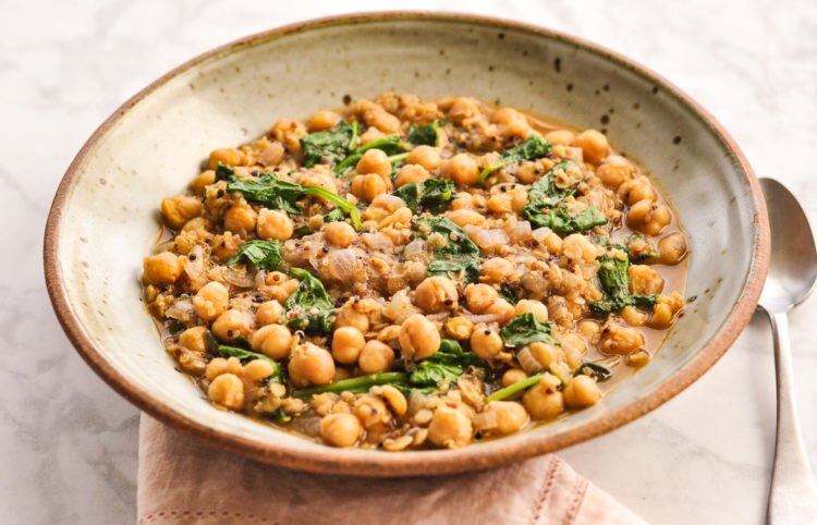 Bowl of very thick soup with chickpeas, lentils, and quinoa, and flecks of wilted spinach