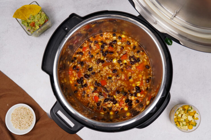 A Mexican soup recipe with beans and tomatoes simmers in an Instant Pot.