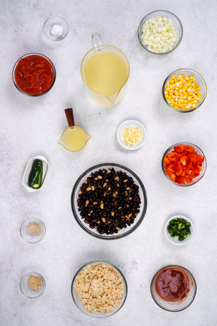 Ingredients for Mexican soup, including tomatoes, beans and corn are plated on a countertop.