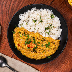 South Indian dal served with basmati rice, surrounded by ingredients including tomatoes and red lentils.