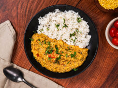 South Indian dal served with basmati rice, surrounded by ingredients including tomatoes and red lentils.