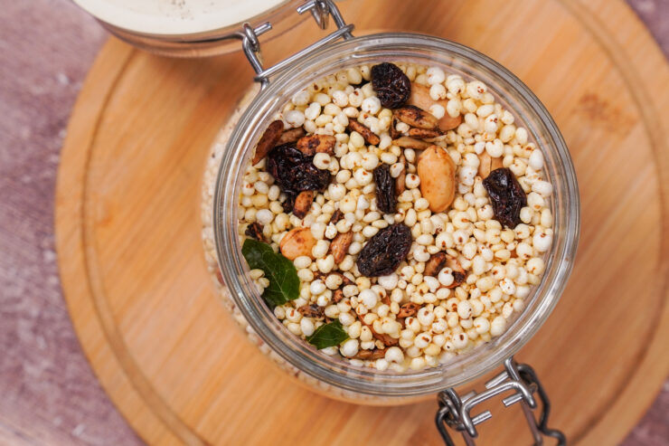 Overhead view of a jar of namkeen sitting on a wooden board. The namkeen is a mixture of puffed millet, spices, peanuts, and sunflower seeds.