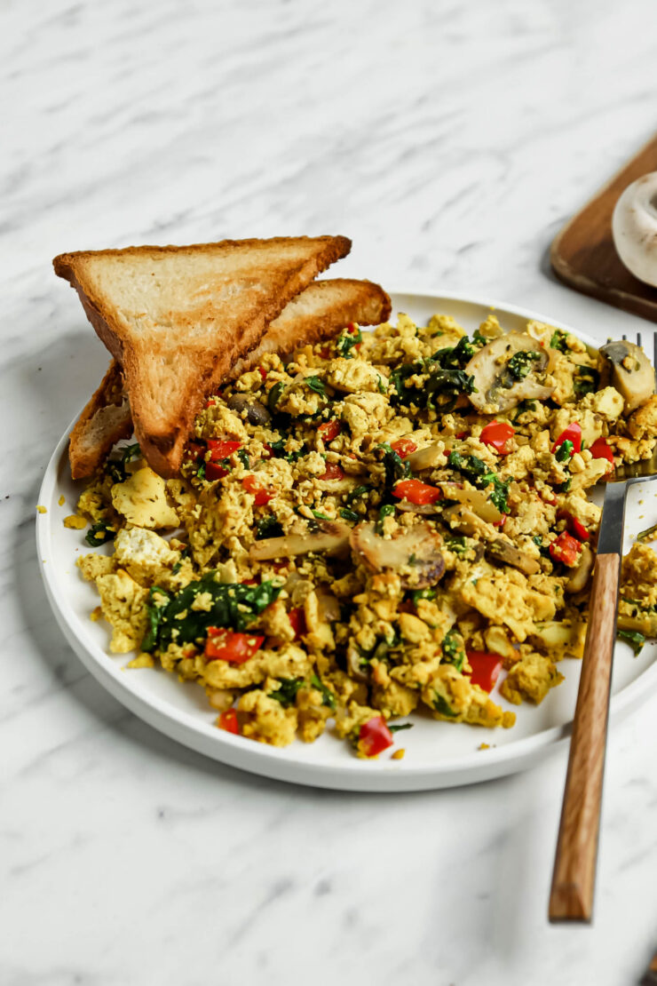 Curried tofu scramble with spinach served alongside two slices of toast.