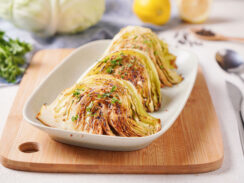 Plated oven-baked cabbage wedges coated in mustard and fresh parsley.