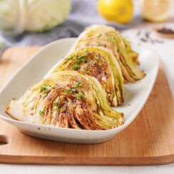 Plated oven-baked cabbage wedges coated in mustard and fresh parsley.