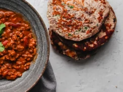 Keto flatbread pieces piled together alongside an Indian curry dish.