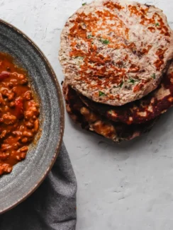 Keto flatbread pieces piled together alongside an Indian curry dish.