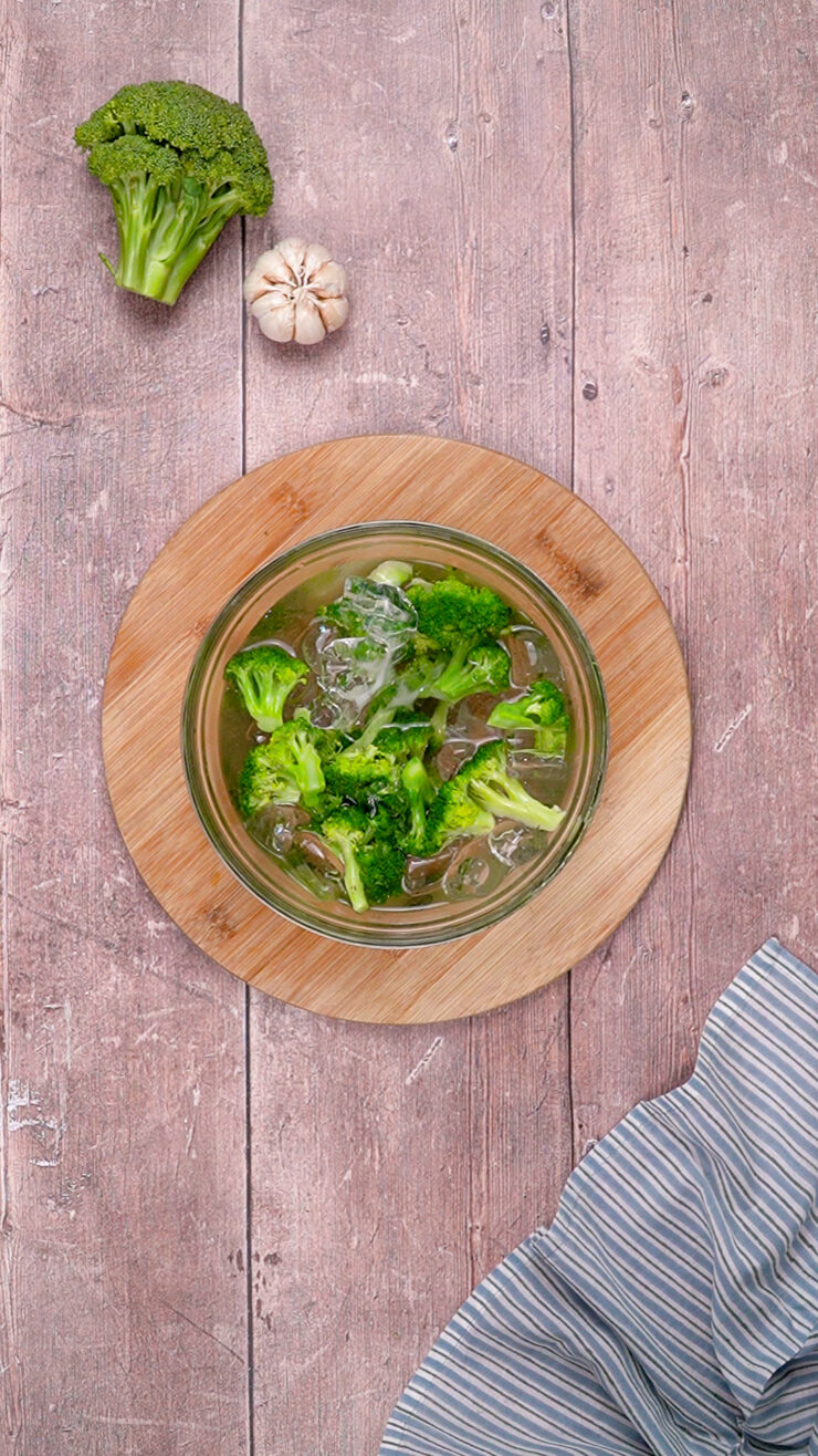 Broccoli florets are plunged into in a bowl of iced water as part of the broccoli blanching process.