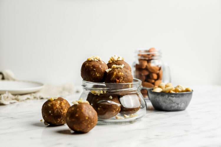 Vegan besan balls in a small jar with some sitting next to it on a white counter