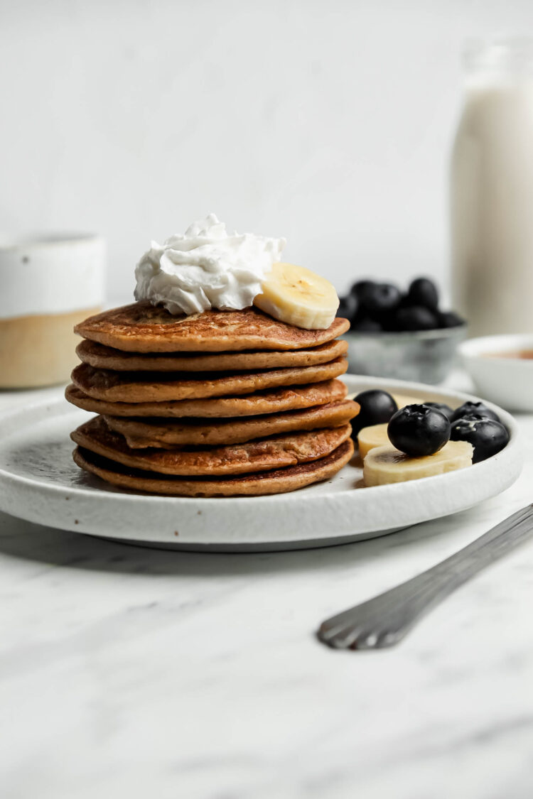 Dairy-free banana pancakes on a plate with whipped cream.