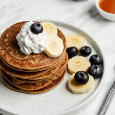 Pancakes with bananas, blueberries, and whipped cream. This is a recipe for dairy-free banana pancakes.