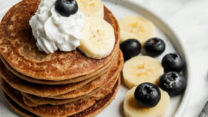 Pancakes with bananas, blueberries, and whipped cream. This is a recipe for dairy-free banana pancakes.