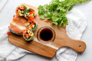 Vegan Vietnamese Spring Rolls on a chefs board with Tamari or Soy Sauce for dipping.