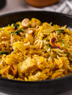 Black bowl filled with Delhi-style biryani which is yellow and studded with vegetables and nuts