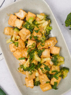 Broccoli stir fry with crispy tofu and green onions in a creamy savory sauce, featured in a guide to the best veggie stir fry recipes.