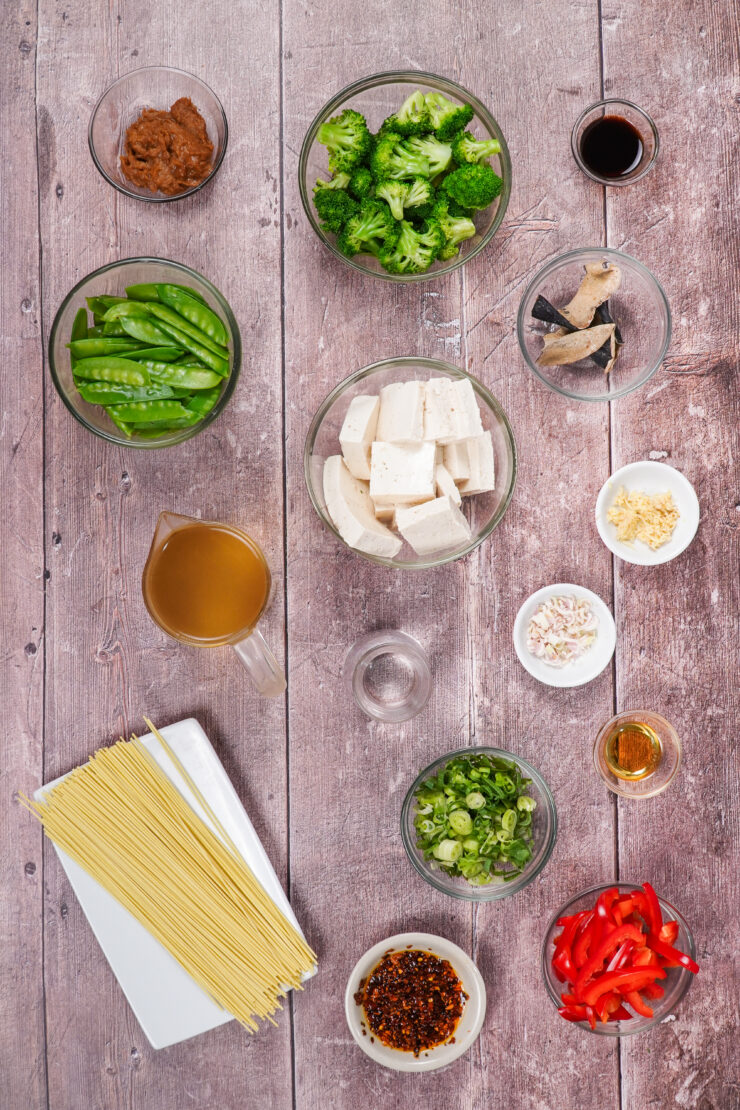 Ingredients for miso soup with tofu, including tofu noodles, green onions, ginger and extra firm tofu.