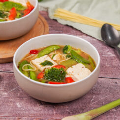 Two bowls of miso soup with tofu, topped with grated dried mushroom and chilli flakes.