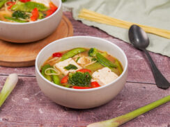 Two bowls of miso soup with tofu, topped with grated dried mushroom and chilli flakes.