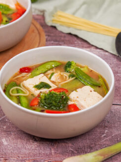 Two bowls of miso soup with tofu, topped with grated dried mushroom and chilli flakes.
