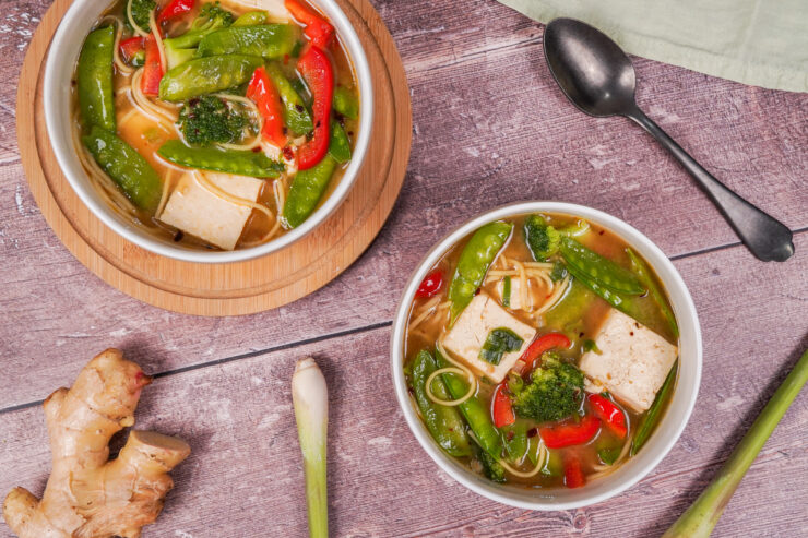 Two bowls of miso soup, with ingredients including tofu, green onion and chilli.